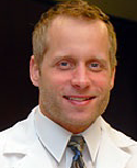 A man in white shirt and tie smiling for the camera.