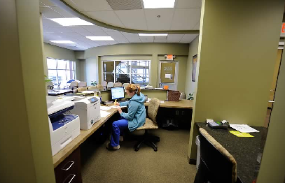 A woman sitting at her computer desk in an office.